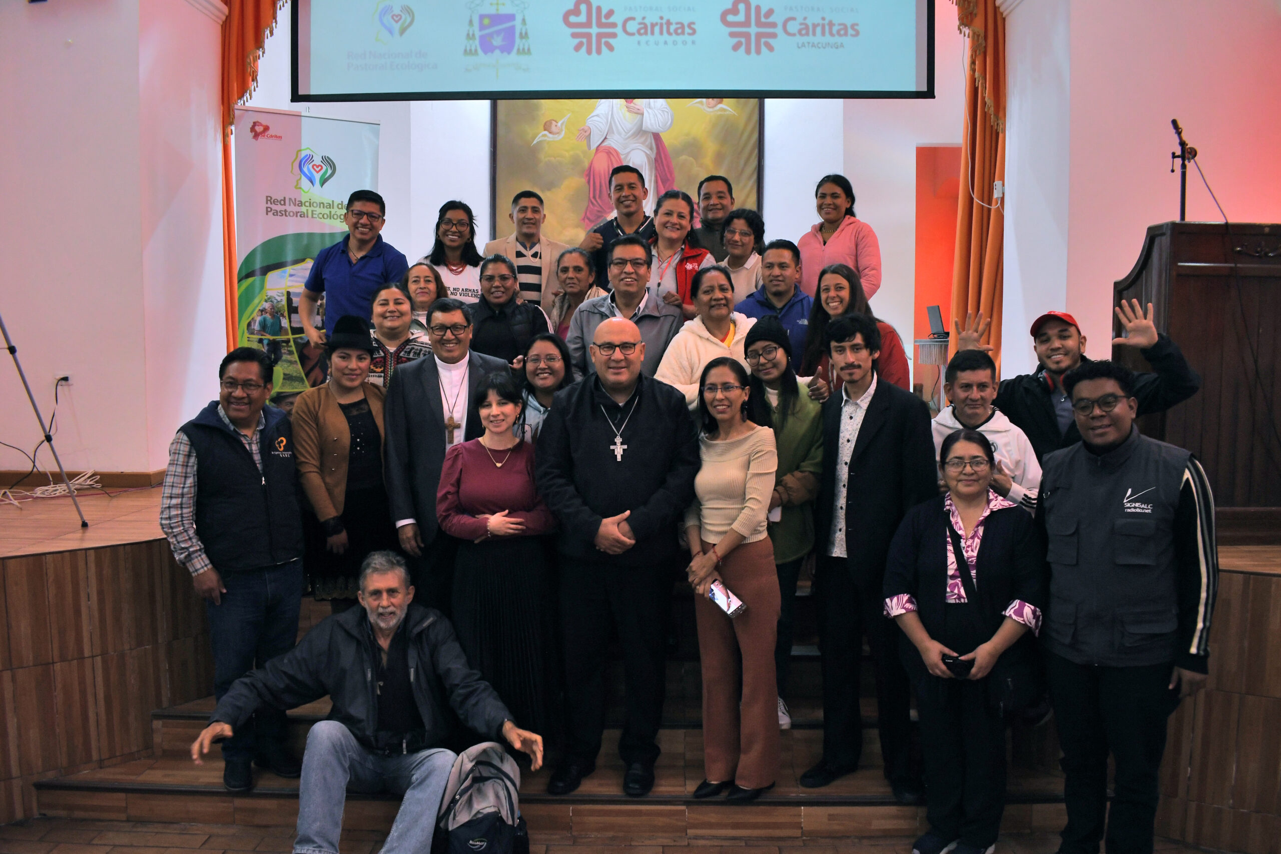 Varias personas sonriendo reunidas en un auditorio